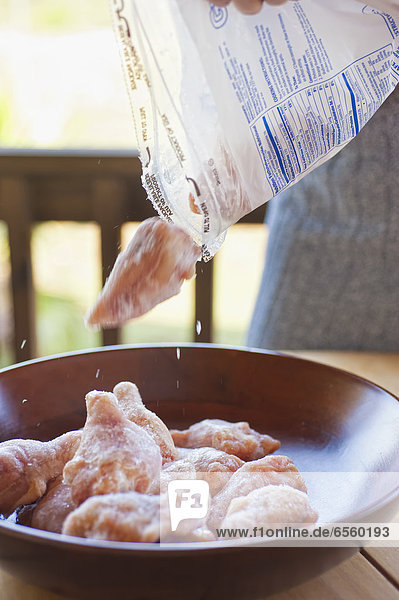 USA  Texas  Reife Frau  die gefrorene Hühnerkeulen in die Schüssel gießt.