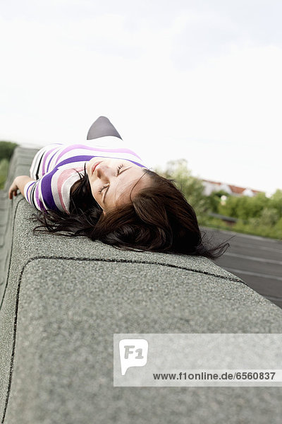 Young woman lying on wall