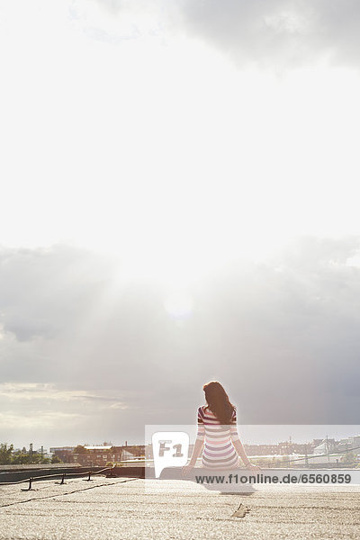 Young woman sitting at edge of roof