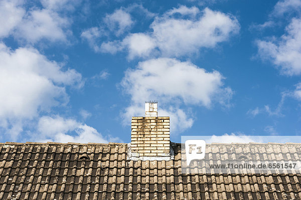 Germany  North Rhine Westphalia  Duesseldorf  View of tiled roof with chimney against clouds