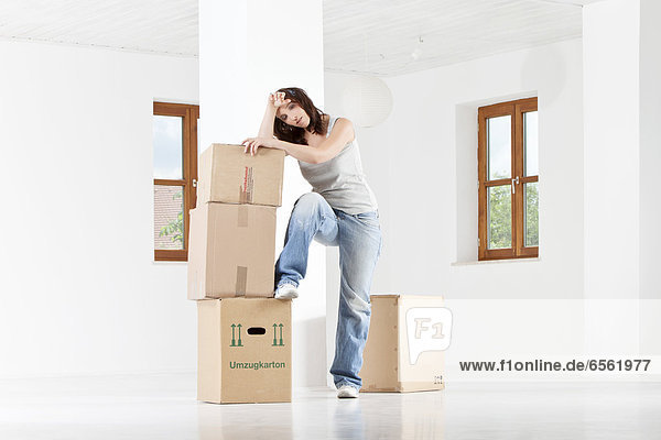 Young woman leaning on cardboard boxes