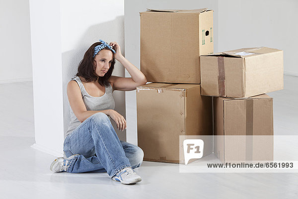 Young woman sitting by cardboard box