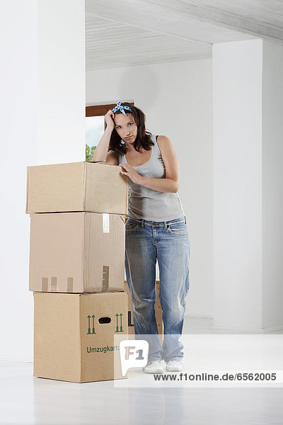 Young woman leaning on cardboard boxes  portrait