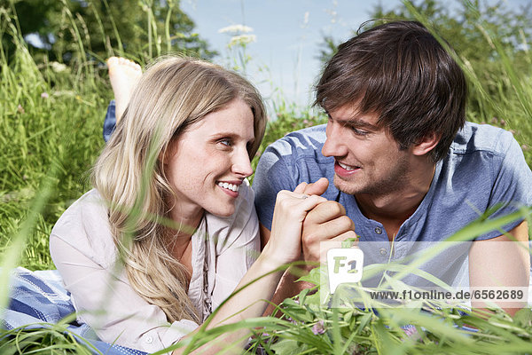 Germany  Cologne  Young couple lying in meadow  smiling