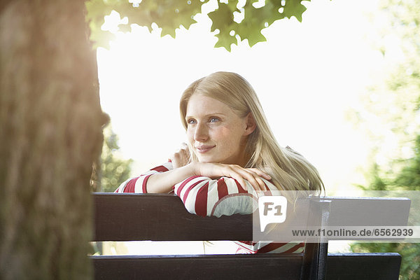 Young woman sitting on park bench  smiling