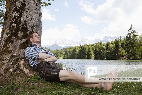 Mid adult man relaxing under tree