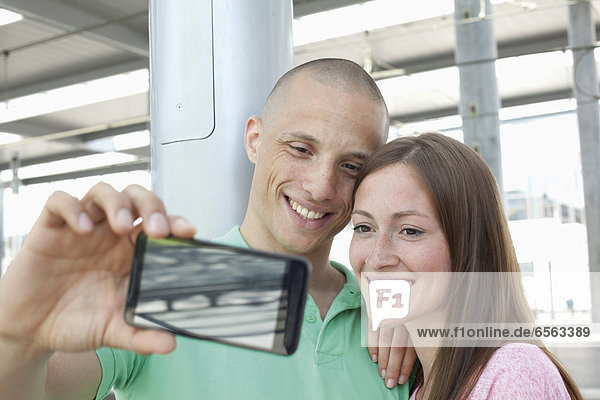 Germany  North-Rhine-Westphalia  Duesseldorf  Young couple photographing self with smart phone