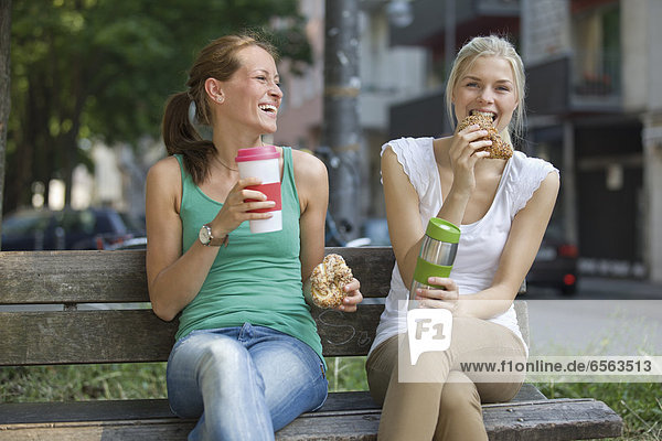 Deutschland  Nordrhein-Westfalen  Köln  Junge Frauen auf der Bank mit Kaffee und Croissants