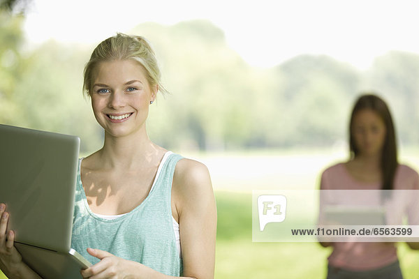 Germany  North Rhine Westphalia  Cologne  Young woman using laptop  smiling