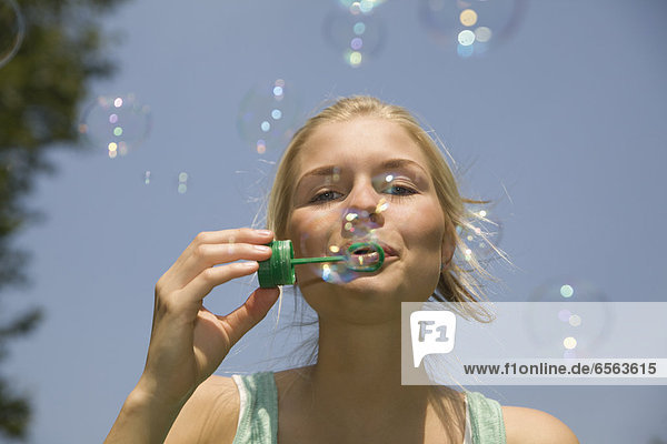 Germany  North Rhine Westphalia  Cologne  Young woman blowing soap bubbles