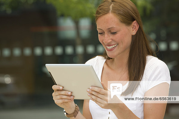Germany  North Rhine Westphalia  Cologne  Young woman with digital tablet  smiling