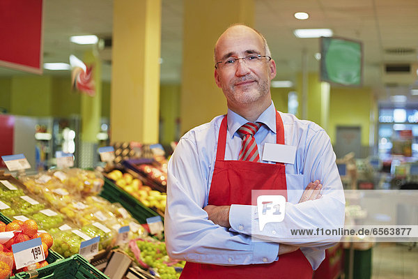 Reifer Mann im Supermarkt stehend  lächelnd  Portrait