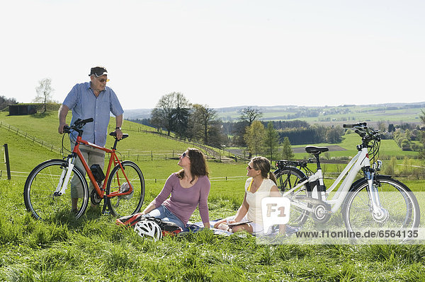 Senior man and mature women talking on hill with electric bicycle