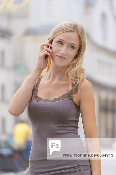 Young woman talking on phone in front of Ludwig Maximilian University