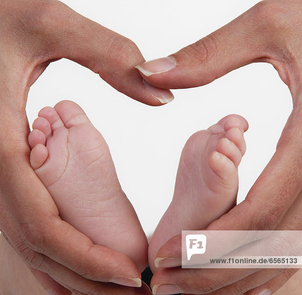 Mutter hält Babys Fuß mit Herzform  Nahaufnahme