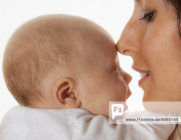 Mutter berührt ihre Nase auf der Stirn des Babys