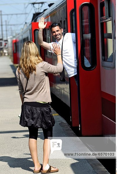 Young couple traveling by train. Goodbyes on a station platform *** Local Caption ***