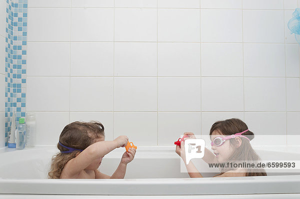 Sisters playing in a bath tub
