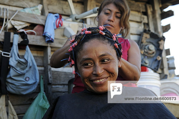 Woman doing another woman's hair in front of her hut  customer is 40 years old  in a poor neighborhood  Cancun  Yucatan Peninsula  Quintana Roo  Mexico  Latin America  North America