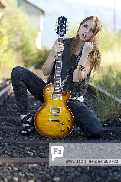 Junge Frau posiert mit E-Gitarre