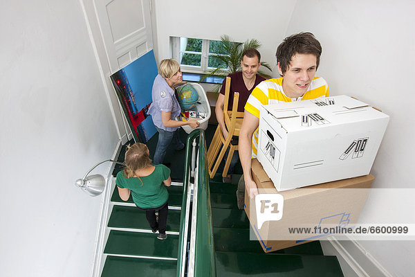 Private house move  friends helping  carrying boxes and furniture up the stairs