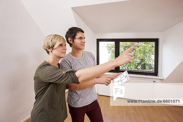 Young couple in a new apartment  planning the furnishings with the aid of an iPad