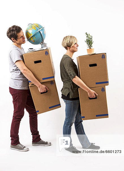 Young couple carrying moving boxes  a globe and a house plant