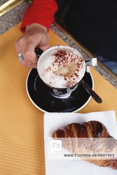 Frau  Tasse  halten  Cafe  Fokus auf den Vordergrund  Fokus auf dem Vordergrund  Cappuccino  Croissant