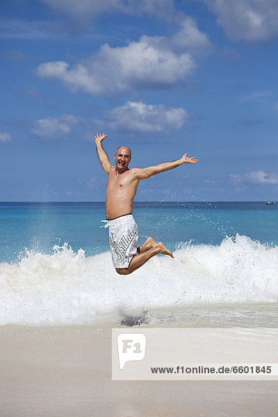 Mann  45 Jahre  macht einen Luftsprung vor Freude am Strand der Anse Intendance  Süd-Mahe  Mahe  Seychellen  Afrika  Indischer Ozean