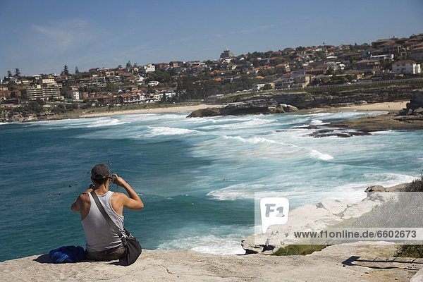 Man Sitting On Rock Over Looking Mackensies And Tamarama Bay  Near Bondi Beach