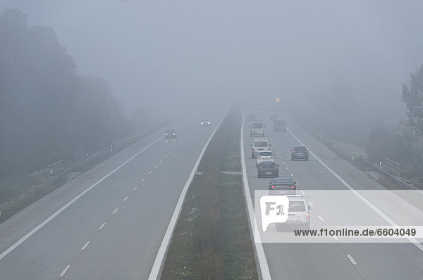 Autobahn im Nebel mit leuchtendem Andreaskreuz als Gefahrenhinweis  bei Freising  Oberbayern  Bayern  Deutschland  Europa
