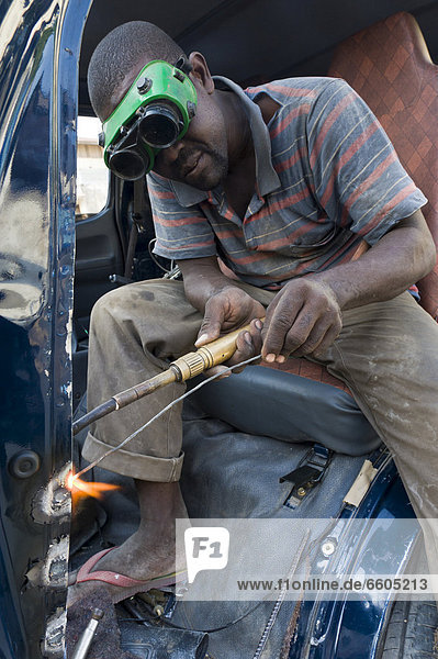 Welder welding the carrossery of a car following an accident  Stone Town  Zanzibar  Tanzania  Africa