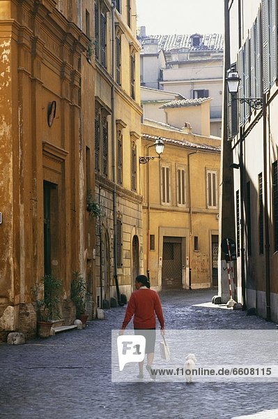 Woman Walking Her Dog Down A Cobbled Back Street In Rome