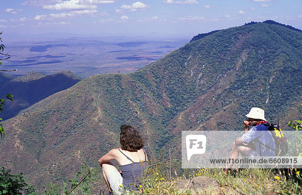 Hikers Sitting On Edge Of Escarpment Overlooking Samburuland