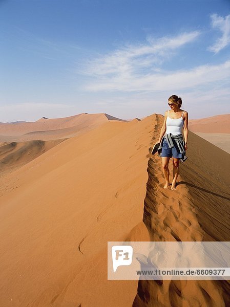 Woman Walking On Top Of Sand Dune In The Desert