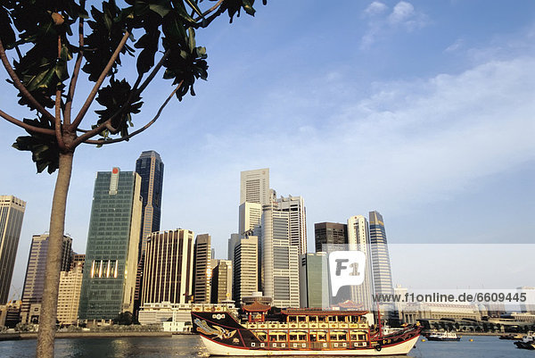 A Chinese Junk In Front Of The Skyline Of Singapore