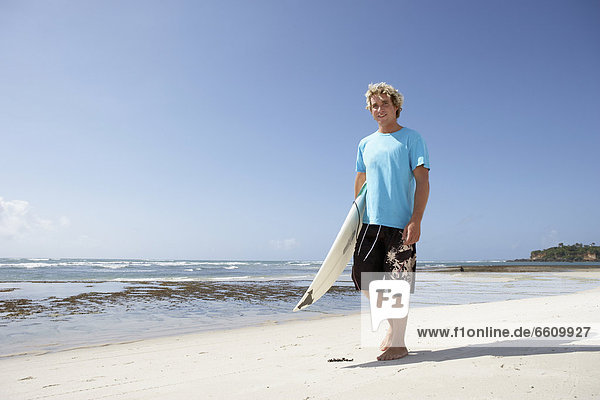Blond Surfer Walking On Beach With Surfboard