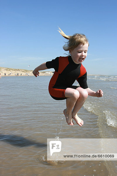 Young Girl In Wetsuit Jumping In Water