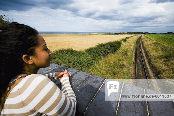 Young woman on bridge overlooking railway tracks