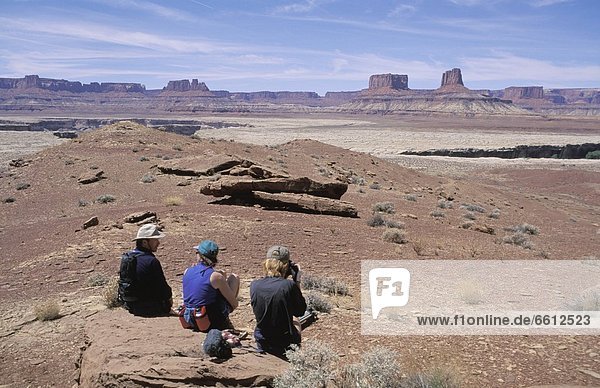 Three hikers relaxing on rock at White Rim