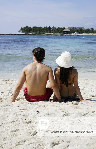 Young couple sitting on beach at Mayan Riviera rear view  Yucatan Peninsular Quintana Roo State Mexico