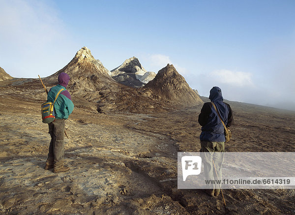 Walkers looking at lava cones shortly after dawn on the summit of Ol Donyo Lengai East Africa's only active volcano Tanzania.