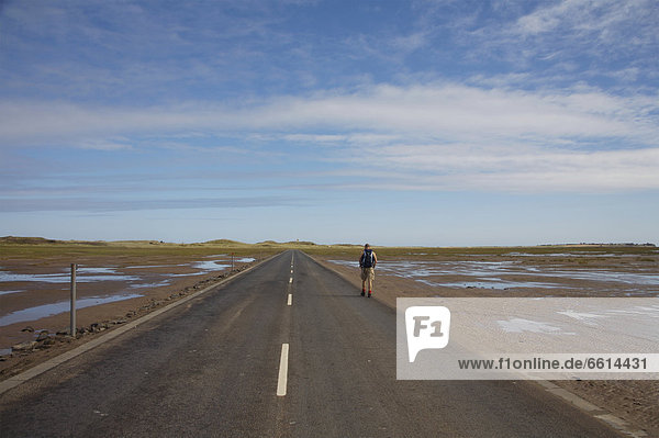 Person walking along road in Lindisfarne  England UK