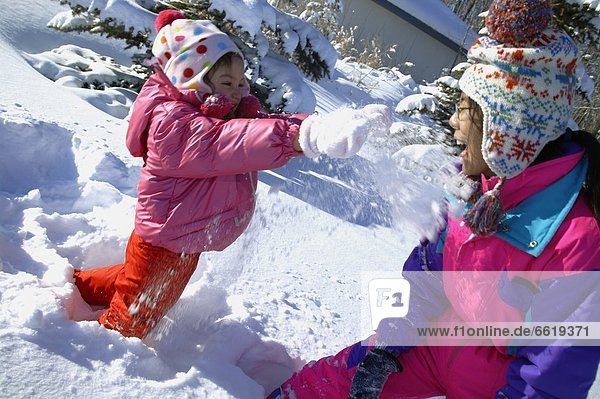 Mother And Daughter Having A Snowball Fight