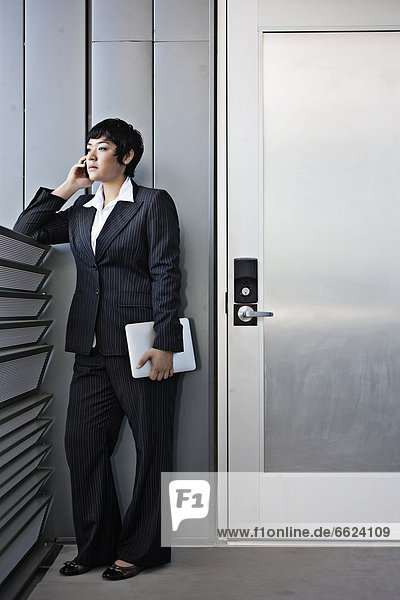 Businesswoman talking on cell phone and holding digital tablet