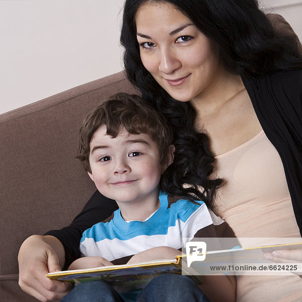 Mixed race mother reading book to son