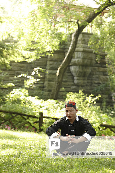 Man in traditional Asian clothing sitting in grass