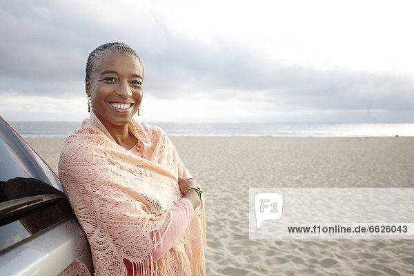 Black woman in shawl standing on beach