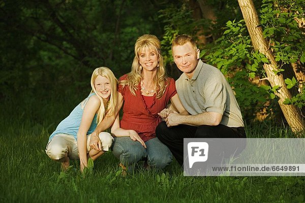 Family Smiling And Sitting In The Park