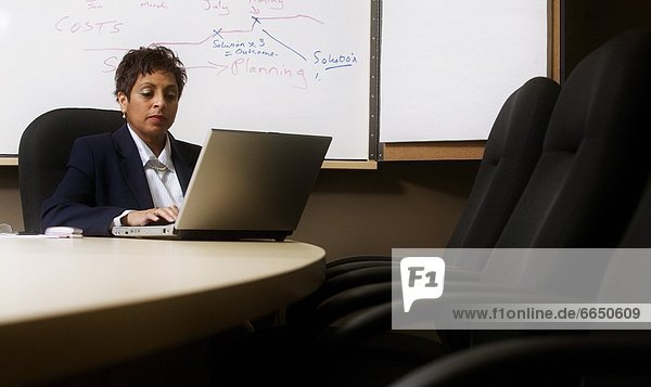 Woman Working On Laptop In Boardroom